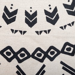 Encerrada por un fino borde de flecos, esta alfombra de algodón presenta motivos geométricos organizados en círculos concéntrico