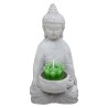 Fabricado en cemento con un acabado rugoso, este portavelas "Buda" representa a un Buda sosteniendo un cuenco en sus manos, en e
